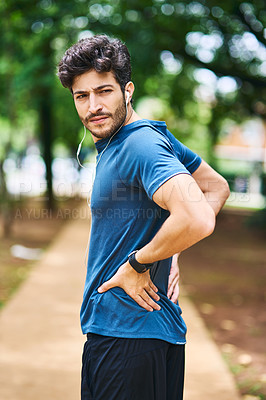 Buy stock photo Shot of a sporty young man holding his back in pain while exercising outdoors