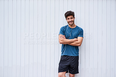 Buy stock photo Wall, portrait and happy man with arms crossed for fitness, wellness and wellbeing journey with workout. Mockup, male person and pride for healthy living, sports podcast with earphones for listening