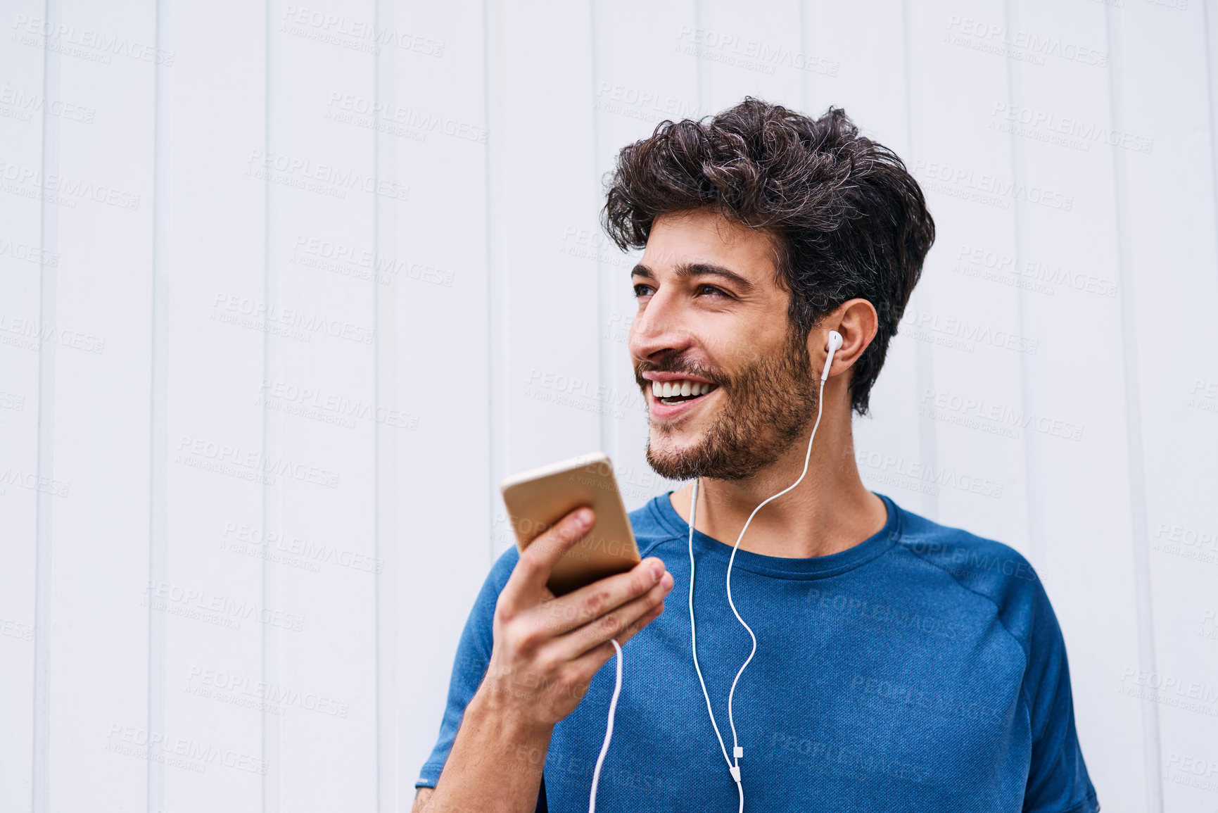 Buy stock photo Shot of a sporty young man listening to music while exercising outdoors