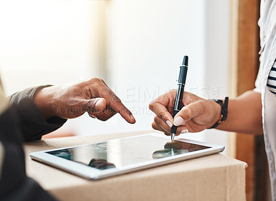 Buy stock photo Closeup shot of an unrecognizable woman using a digital tablet to sign for her delivery from the courier