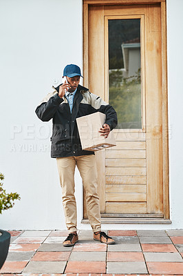 Buy stock photo Shot of a courier talking on a cellphone while making a delivery