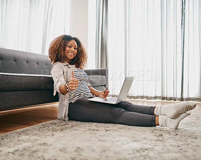 Buy stock photo Portrait of a cheerful young woman doing online shopping on her laptop while being seated on the floor at home