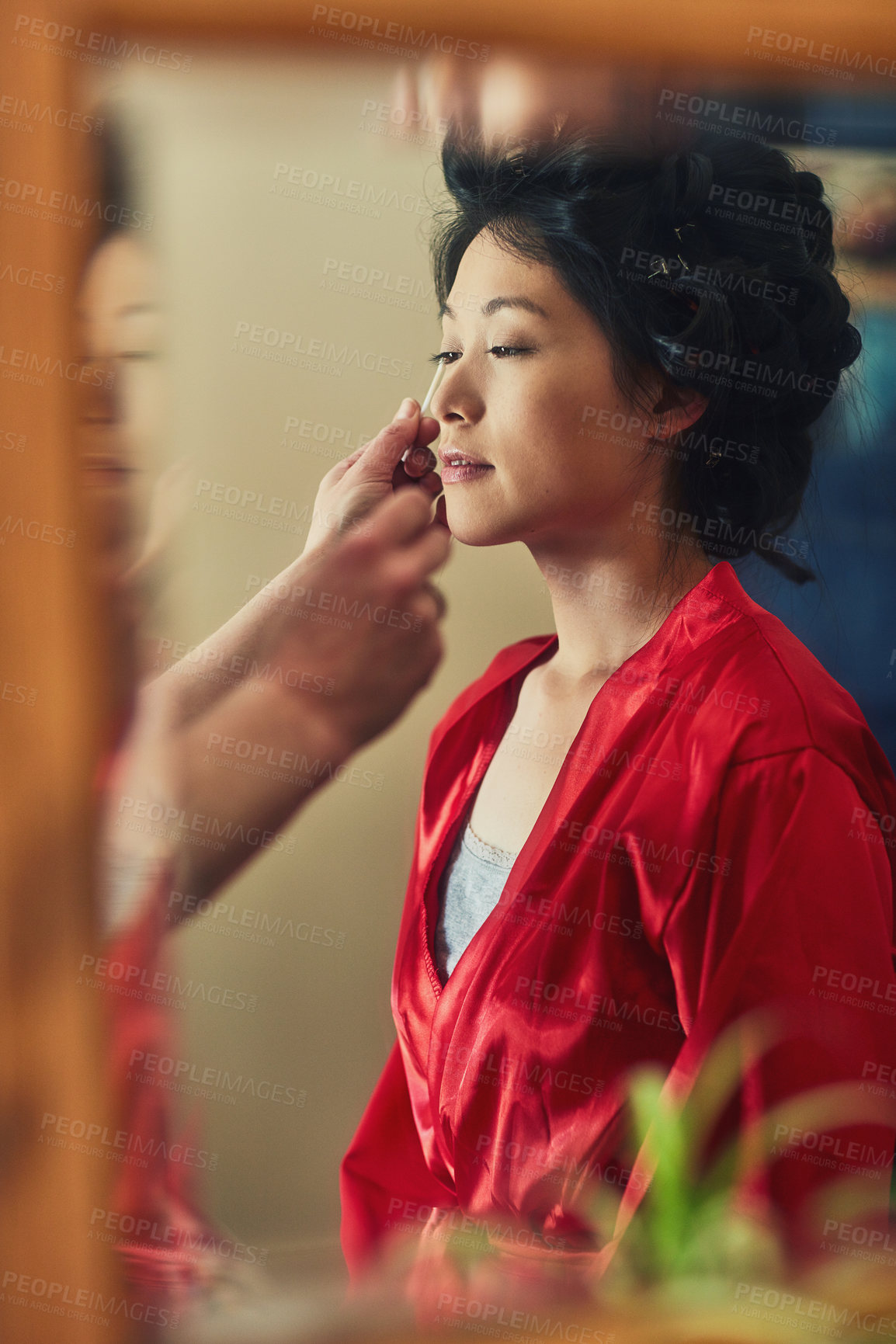 Buy stock photo Shot of a relaxed young woman's reflection in a mirror who's seated on a chair while getting her makeup done before a wedding