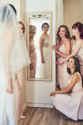 Buy stock photo Shot of a confident young bride looking at her reflection in a mirror while her bride's mades look a her