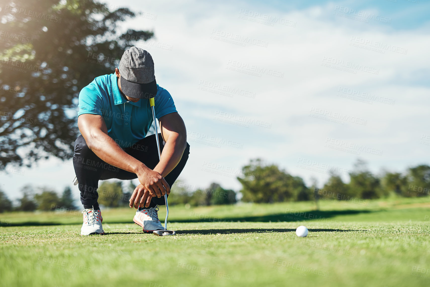 Buy stock photo Shot of a focused young male golfer looking at the ground while being seated on the grass outside during the day