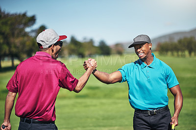 Buy stock photo Shot of two cheerful young male golfers engaging in a handshake after a great shot on the golf course