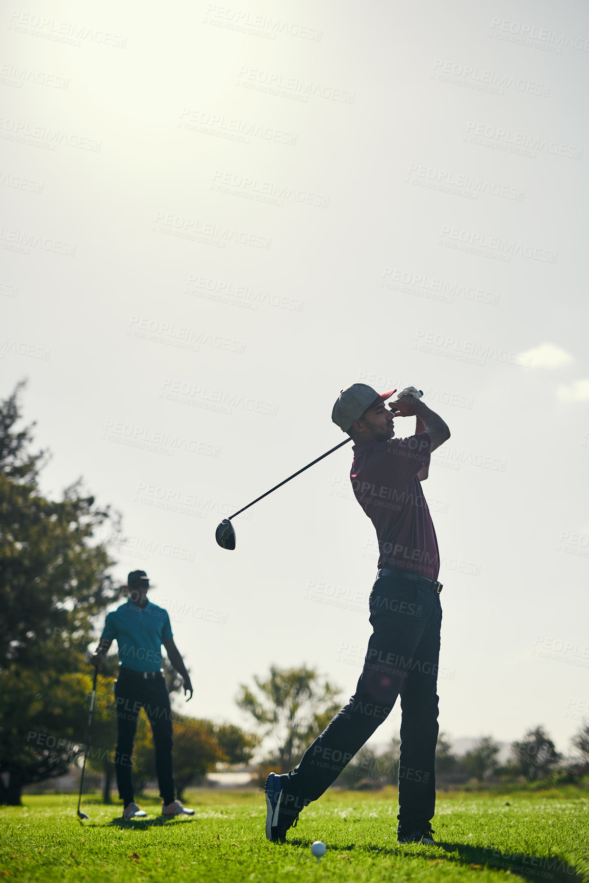 Buy stock photo Shot of a focused young male golfer about to swing and play a shot with his golf club outside on a course