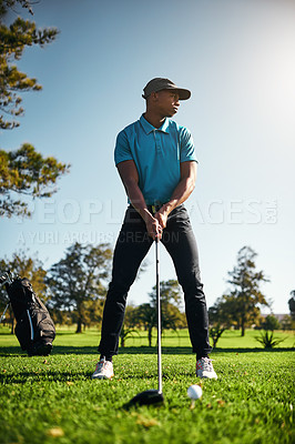 Buy stock photo Shot of a focused young male golfer about to swing and play a shot with his golf club outside on a course