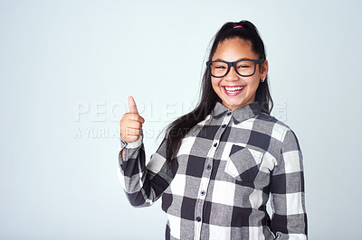 Buy stock photo Portrait, smile and girl with thumbs up, support and feedback on grey studio background. Face, model and happy kid with hand gesture, child and agreement with review, choice and decision with glasses