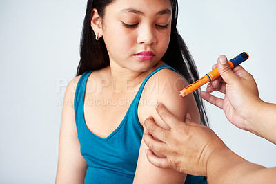Buy stock photo Studio shot of a cute young girl getting an insulin shot from an unrecognizable woman against a gray background
