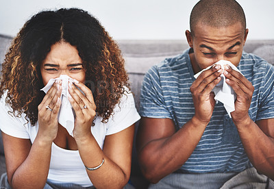 Buy stock photo Shot of a young couple blowing their noses at home