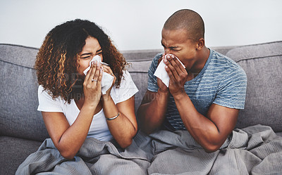 Buy stock photo Shot of a young couple blowing their noses at home