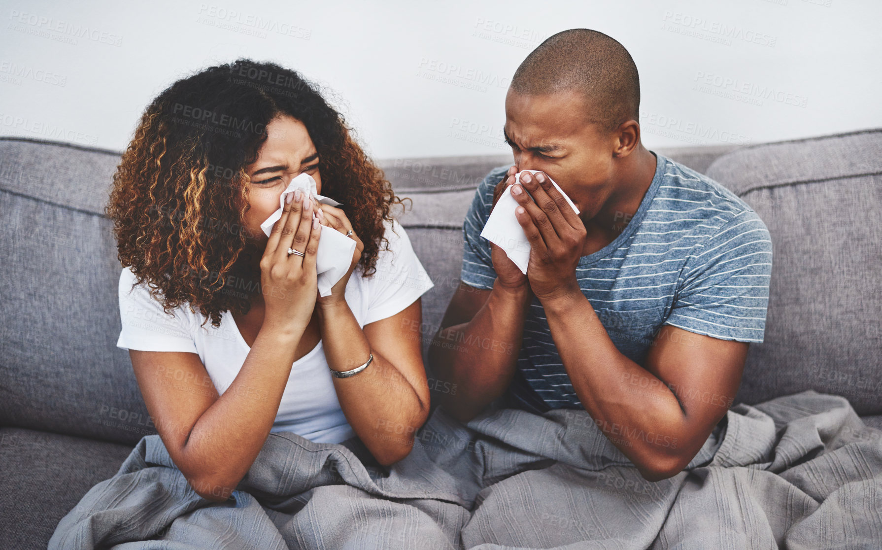 Buy stock photo Shot of a young couple blowing their noses at home