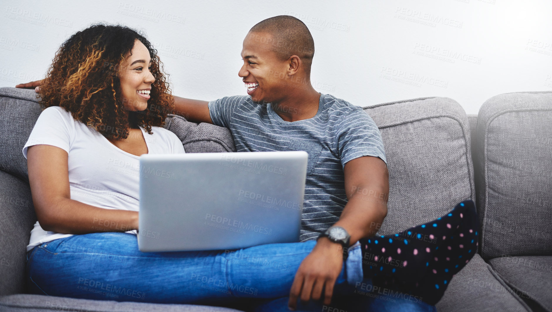 Buy stock photo Shot of a young couple using a laptop while relaxing at home