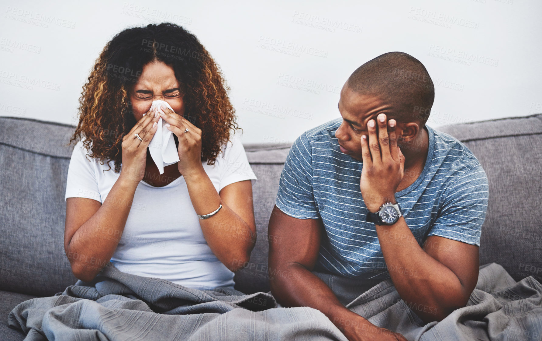 Buy stock photo Shot of a young man getting irritated by his girlfriend suffering with allergies at home