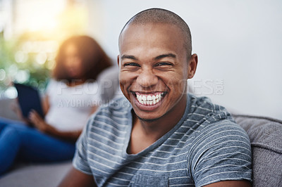 Buy stock photo Portrait of a young man relaxing at home with his girlfriend in the background