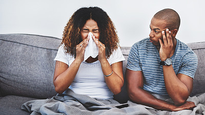 Buy stock photo Shot of a young man getting irritated by his girlfriend suffering with allergies at home