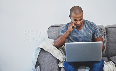 Buy stock photo Shot of a handsome young man using a laptop at home