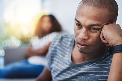 Buy stock photo Shot of a young man looking upset after having a fight with his partner at home