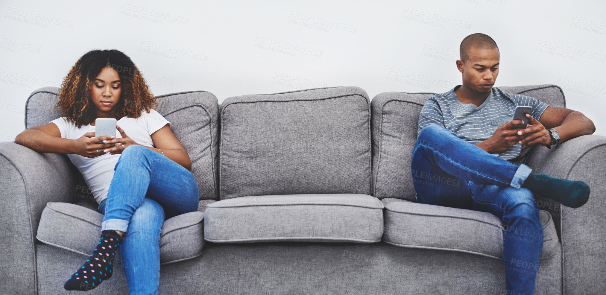 Buy stock photo Shot of a young couple sitting on the sofa after an argument