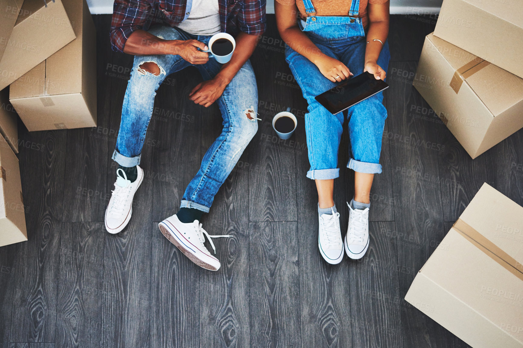 Buy stock photo Tablet, coffee and couple moving with boxes planning their new house together on living room floor. Technology, caffeine and top view of man and woman doing property research on mobile in their home.