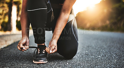 Buy stock photo Cropped shot of an unrecognizable woman tying her shoelaces