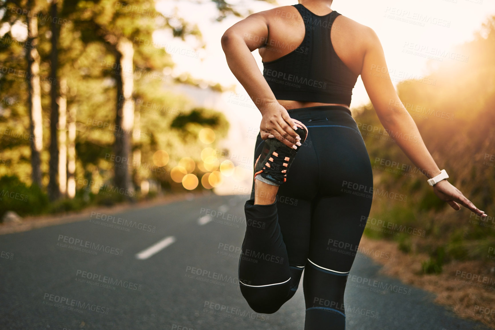 Buy stock photo Rearview shot of a young woman stretching before her run