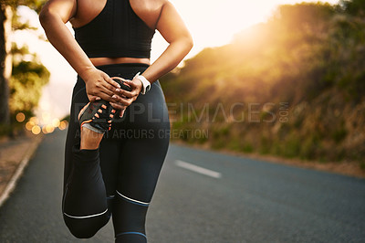 Buy stock photo Cropped shot of an unrecognizable young woman stretching before her run