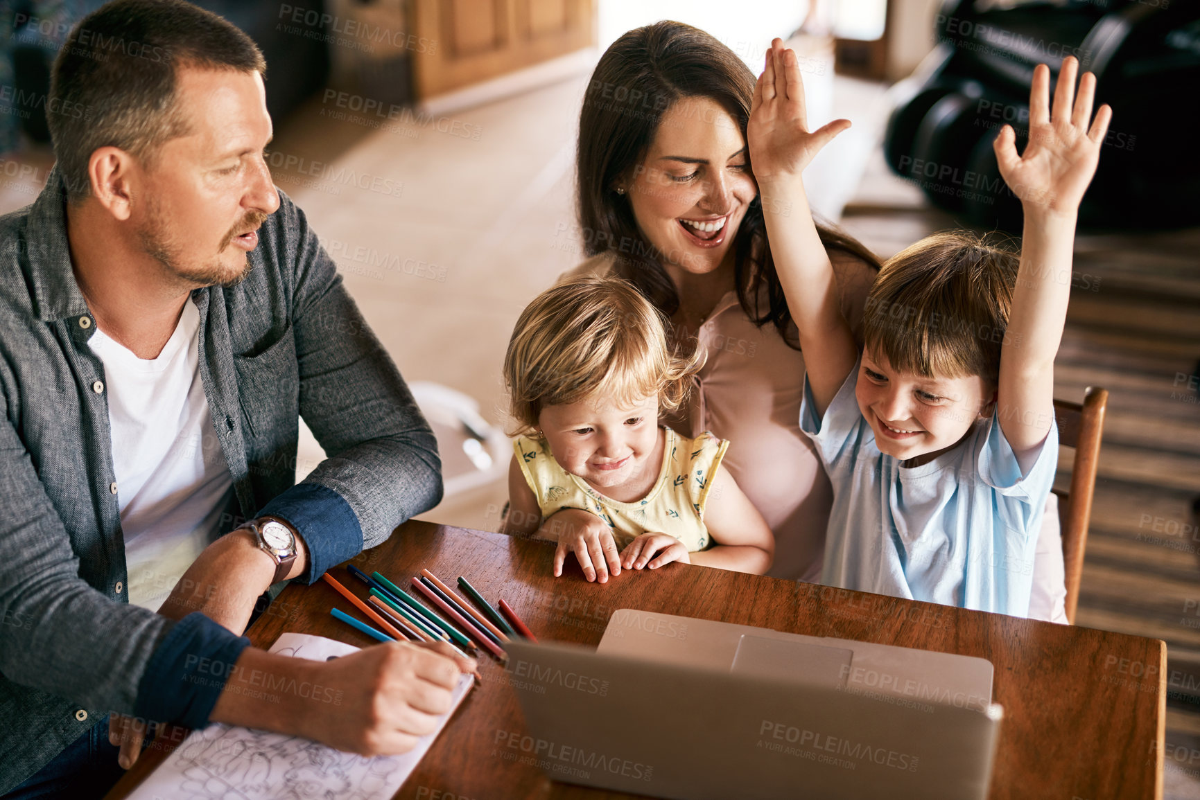 Buy stock photo Shot of a little boy raising his arms enthusiastically while using a laptop with his family at home