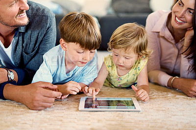 Buy stock photo Shot of a young family of four using a digital tablet together at home