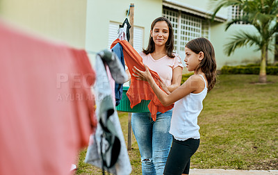 Buy stock photo Shot of a mother and daughter hanging up laundry together outside