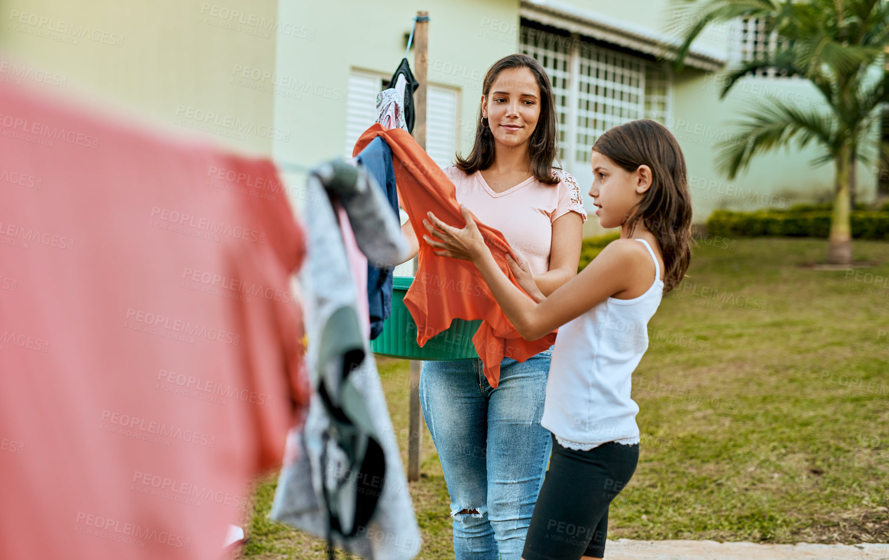 Buy stock photo Shot of a mother and daughter hanging up laundry together outside