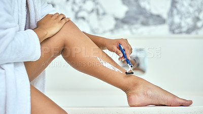 Buy stock photo Shot of an unrecognizable woman shaving her legs with a razor in the bathroom at home during the day