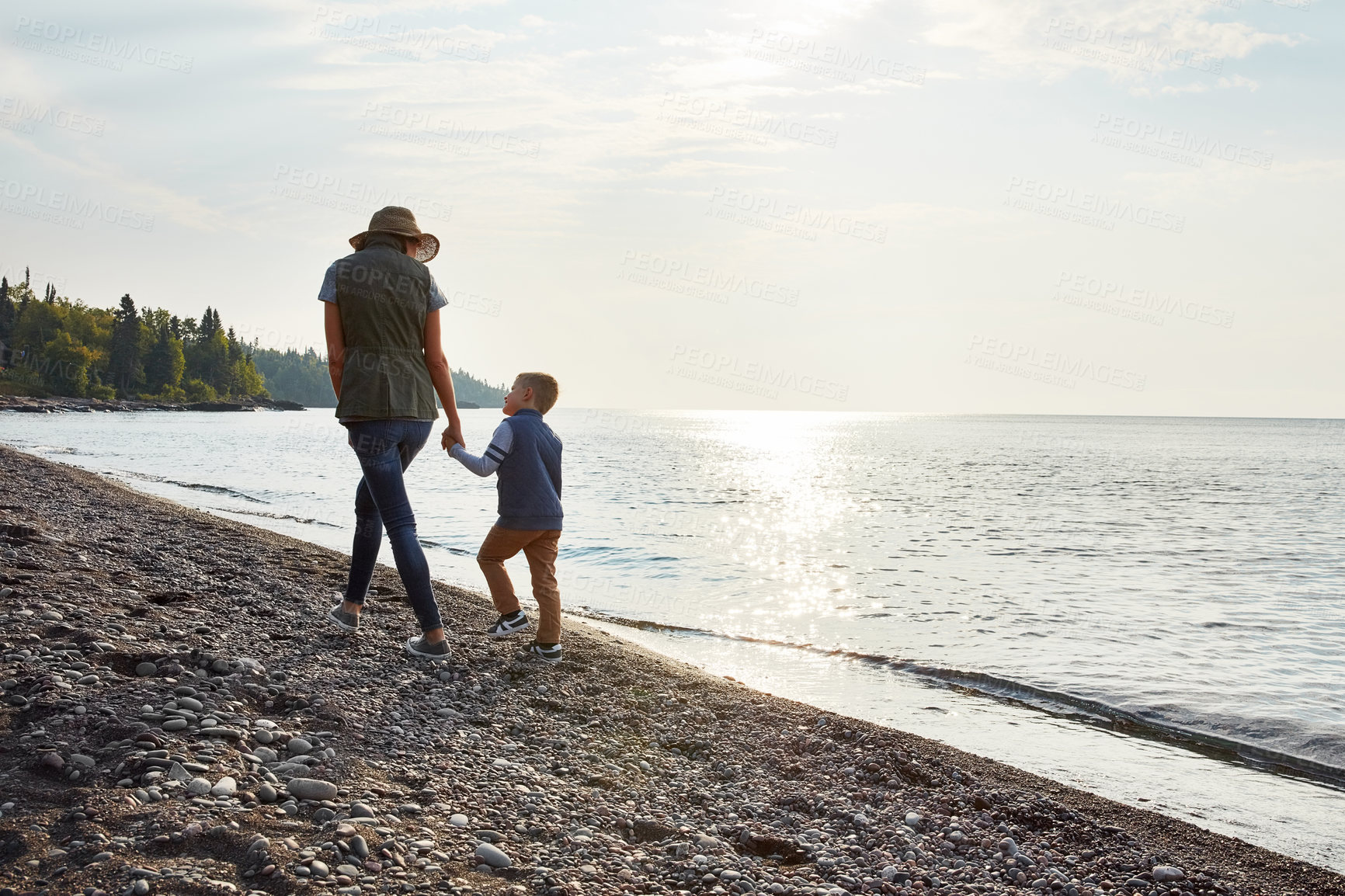 Buy stock photo Shot of a young woman and her son enjoying a walk by the water