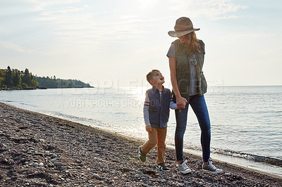 Buy stock photo Shot of a young woman and her son enjoying a walk by the water