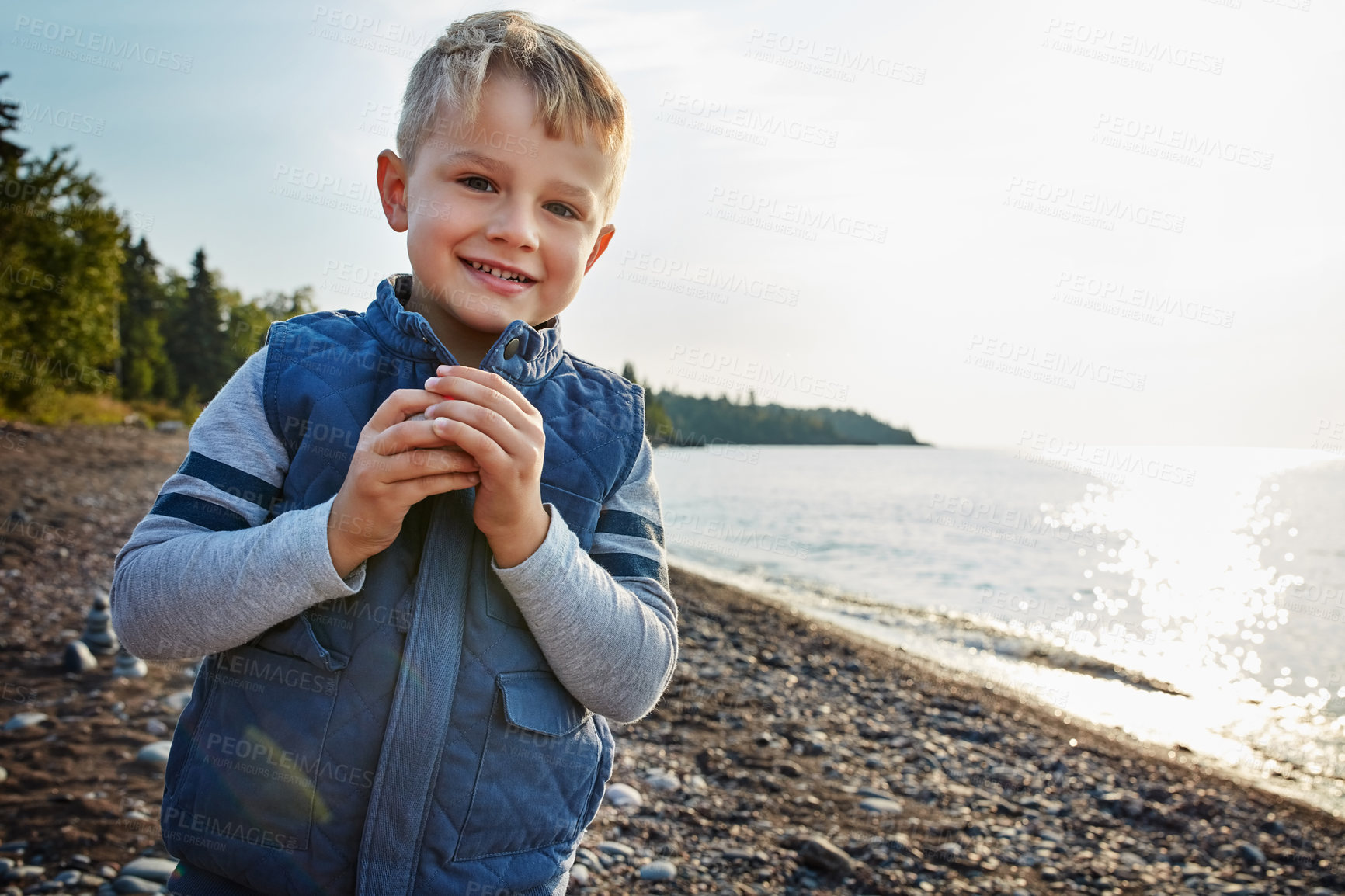 Buy stock photo Cropped shot of an adorable young boy playing outside near a lake