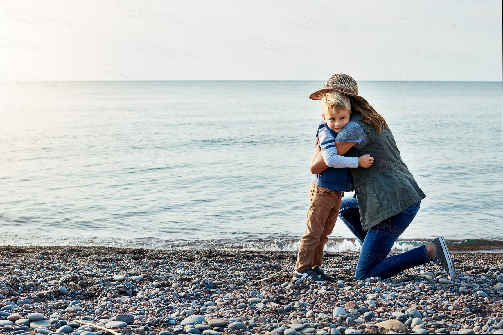 Buy stock photo Shot of a loving mother hugging her son while out by the lake
