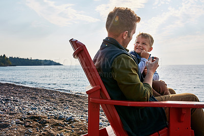 Buy stock photo Shot of a handsome young father and his son enjoying a day by the lake