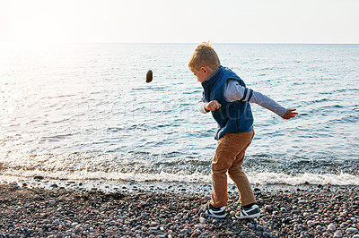 Buy stock photo Shot of a little boy throwing a rock into the lake