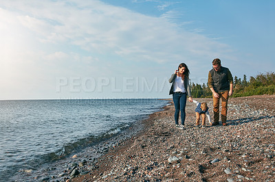 Buy stock photo Shot of a young family walking by the lake