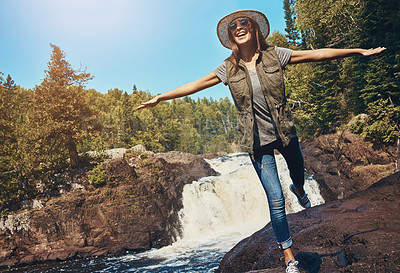 Buy stock photo Shot of a young woman having fun next to a rocky river and waterfall