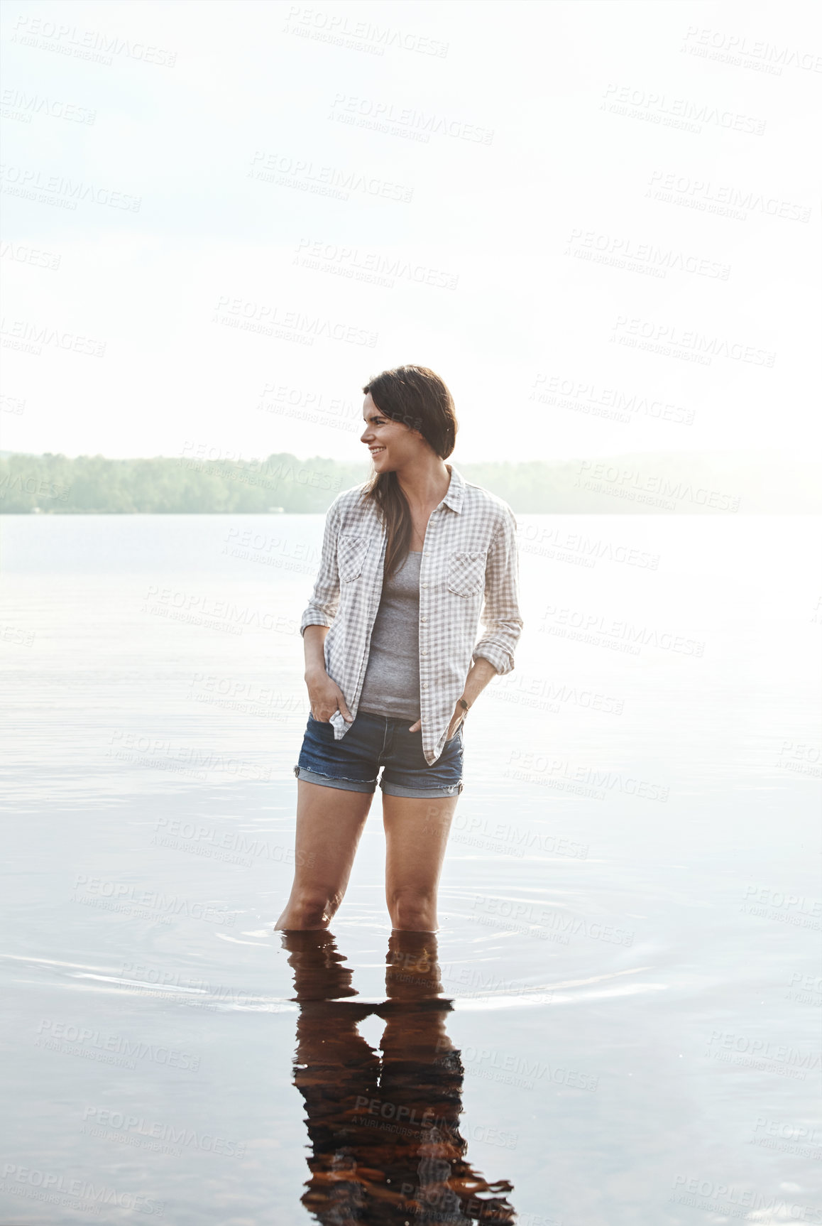 Buy stock photo Shot of an attractive young woman standing in a lake
