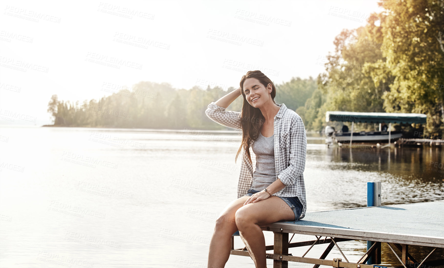 Buy stock photo Shot of an attractive young woman sitting on a pier