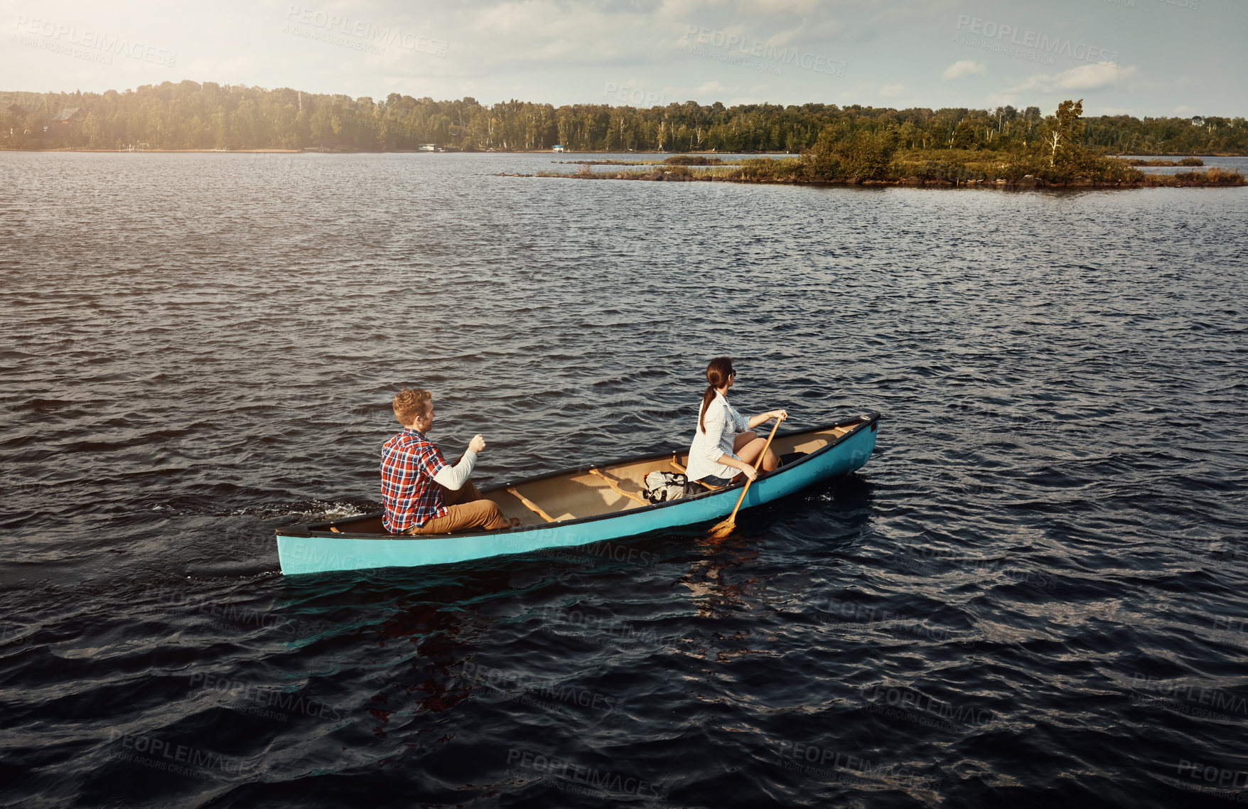 Buy stock photo Shot of a young couple rowing a boat out on the lake