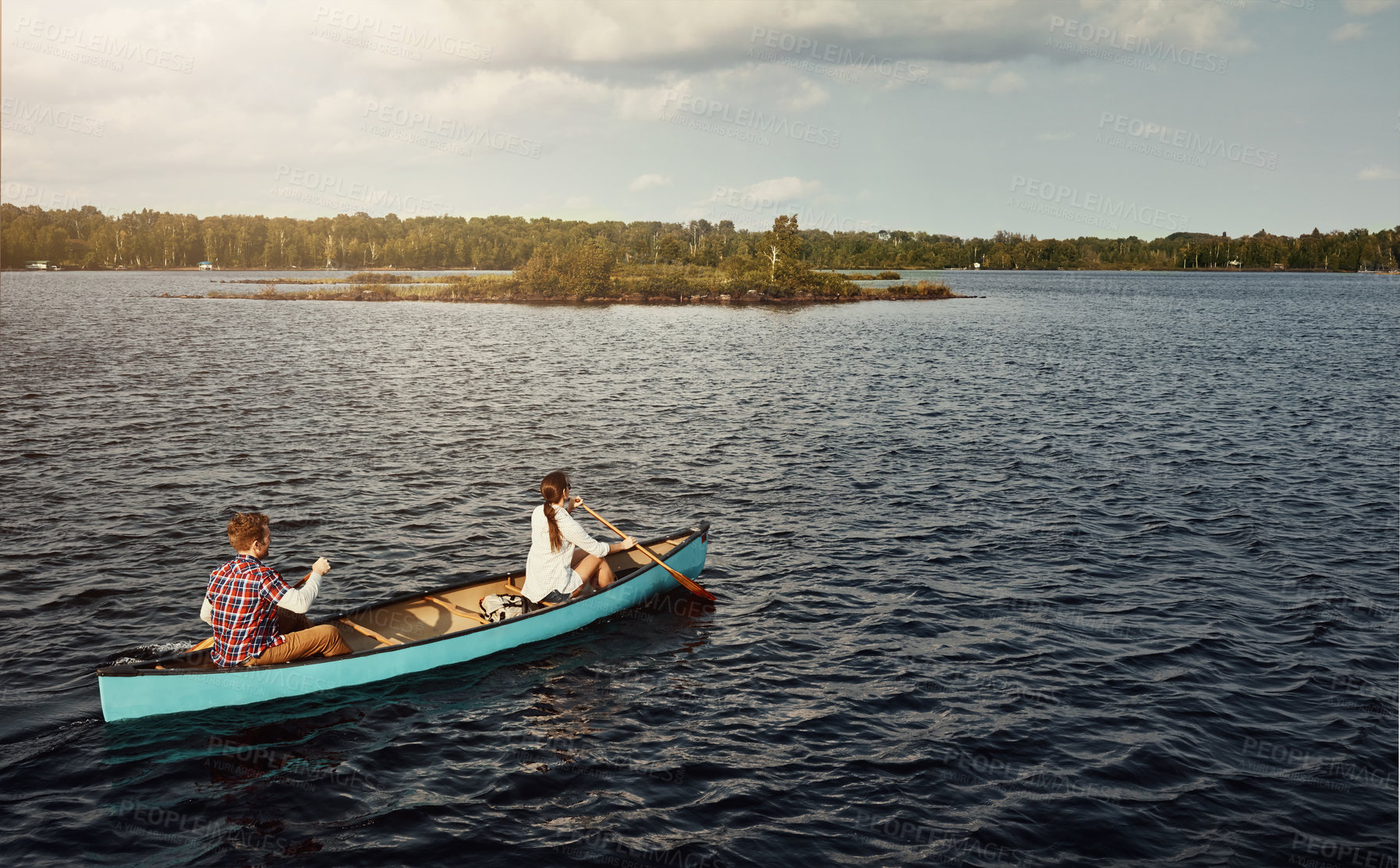 Buy stock photo Shot of a young couple rowing a boat out on the lake