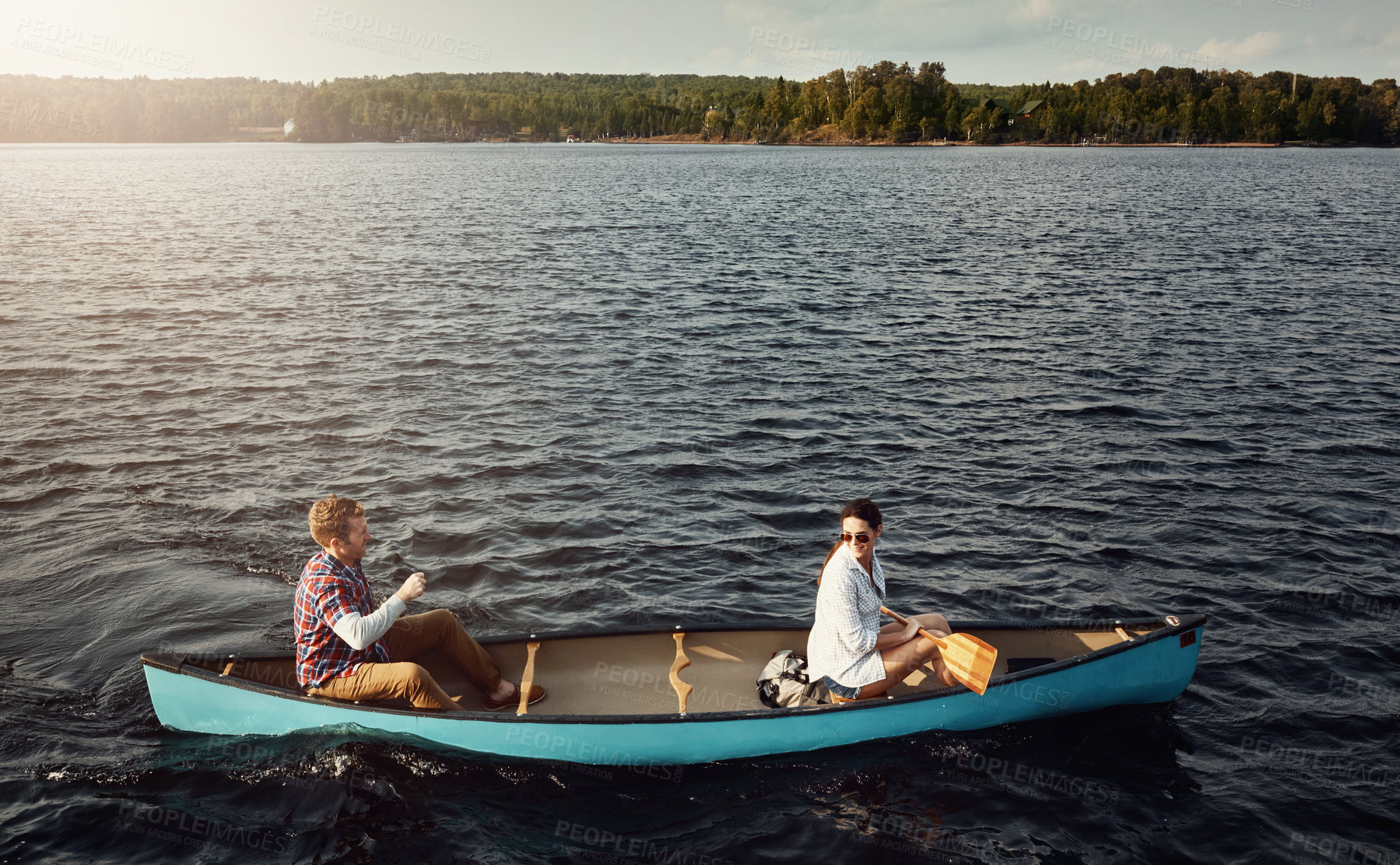 Buy stock photo Shot of a young couple rowing a boat out on the lake