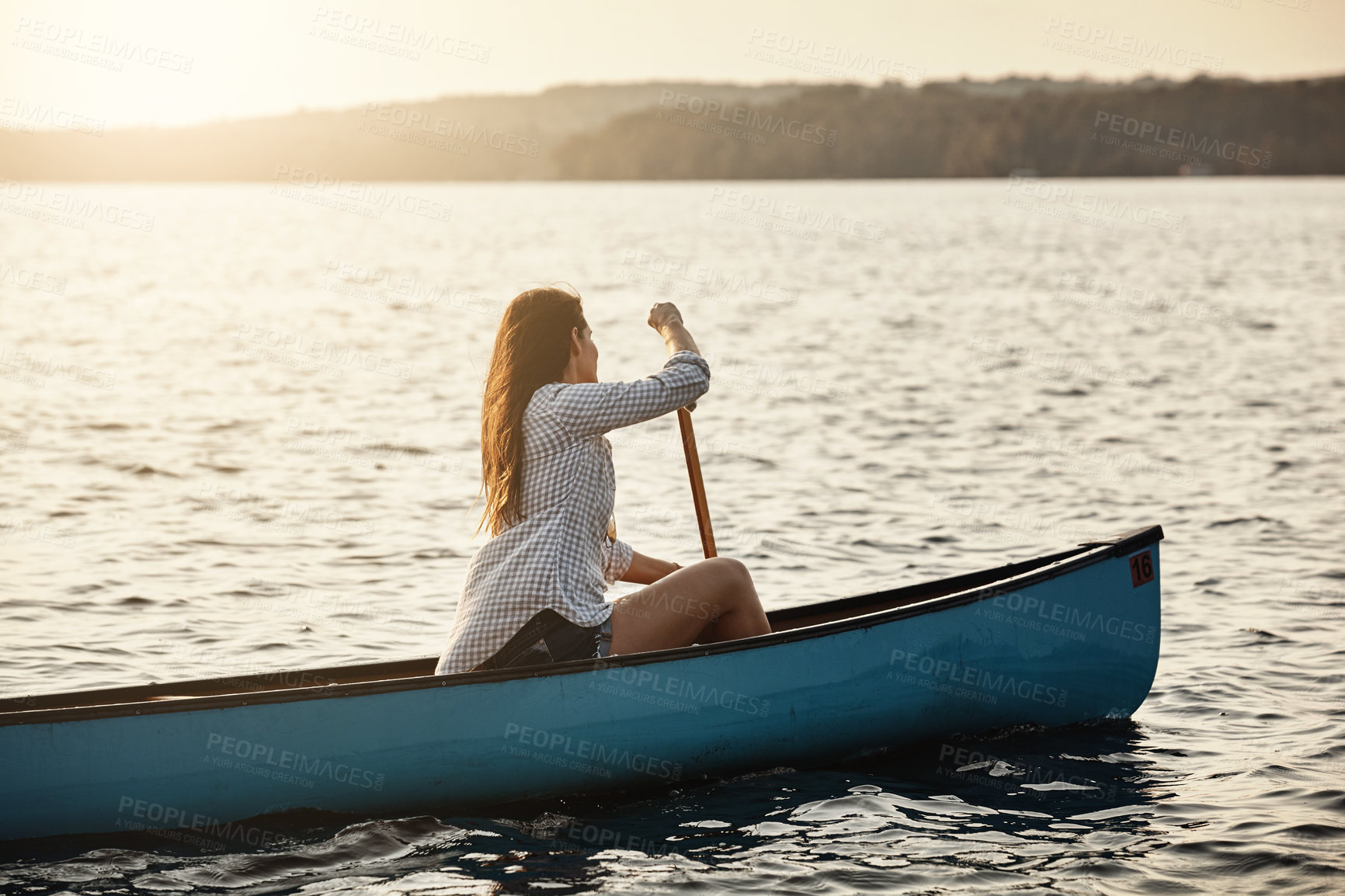 Buy stock photo Shot of a beautiful young woman rowing a boat out on the lake