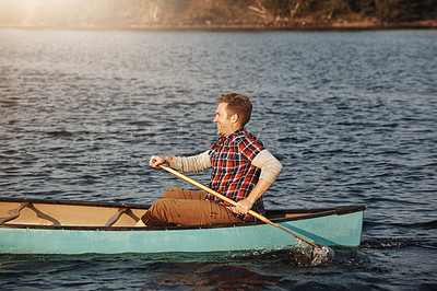 Buy stock photo Shot of a young man rowing a boat out on the lake