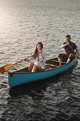 Buy stock photo Shot of a young couple rowing a boat out on the lake