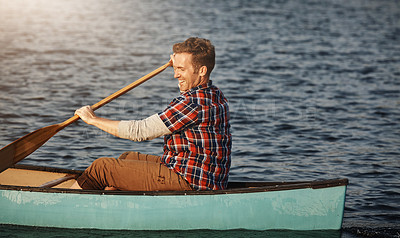 Buy stock photo Shot of a young man rowing a boat out on the lake